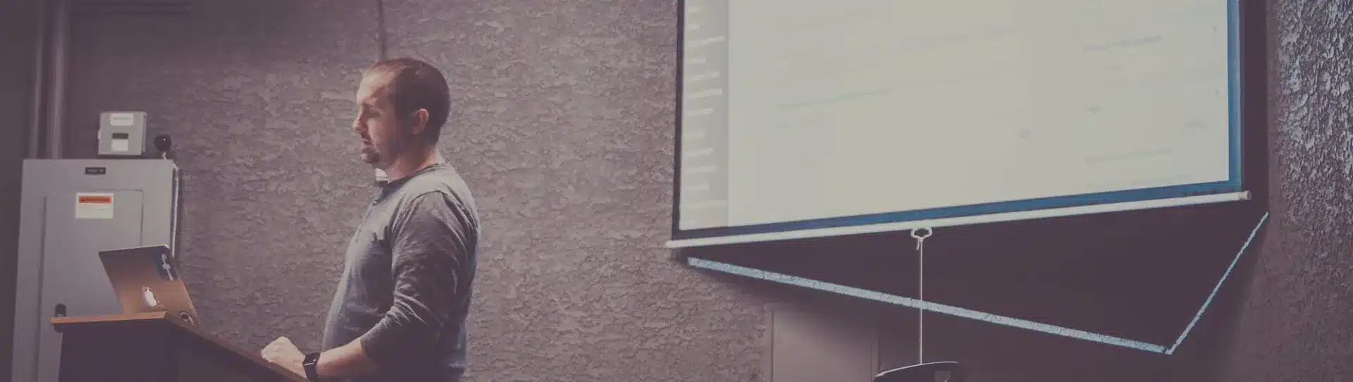 Mann steht vor einer großen Leinwand und präsentiert