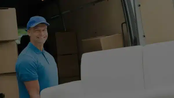 Weiße Couch wird von zwei Möbelpackern in einen LKW verladen