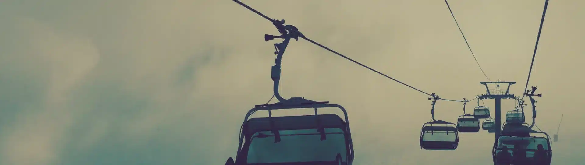 Sessellift fährt Ski und Snowboard Fahrer:innen nach oben auf den Berg